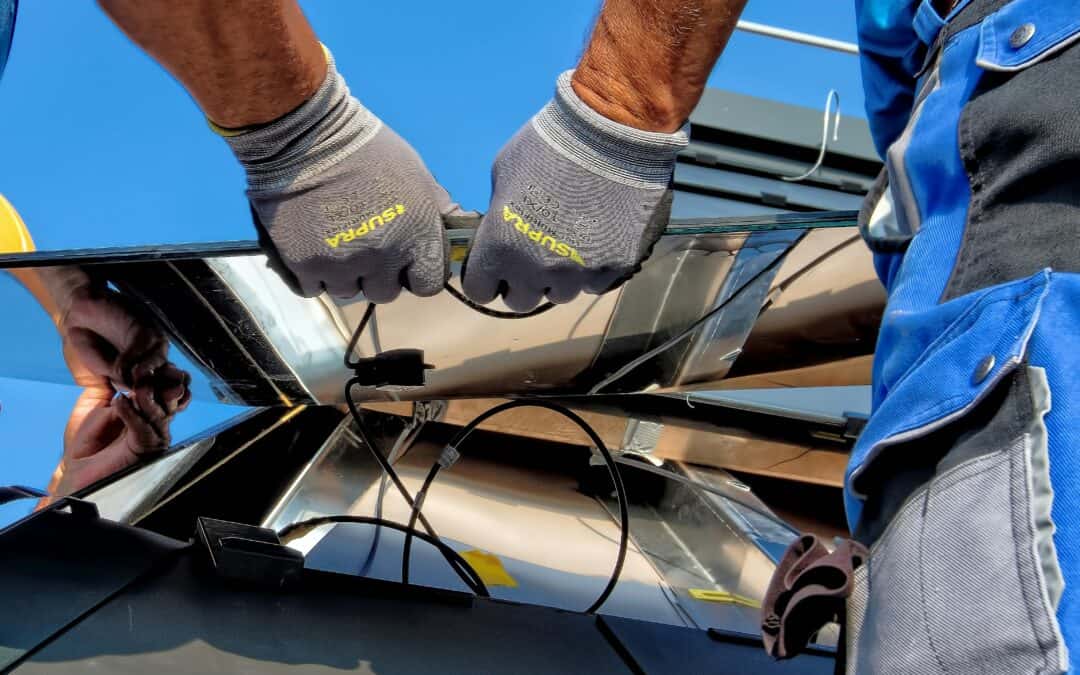 Gloved people install solar panels on a roof